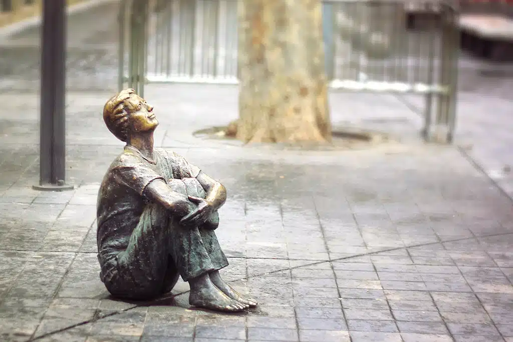 Estatua de bronce de un niño que mira hacia lo alto de la Torre Nueva de Zaragoza, como si todavía existiese (plaza San Felipe).